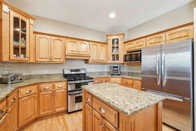 kitchen featuring stainless steel appliances, light wood-style flooring, light stone countertops, recessed lighting, and a kitchen island