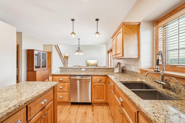 kitchen with stainless steel dishwasher, a sink, light wood-type flooring, pendant lighting, and a peninsula