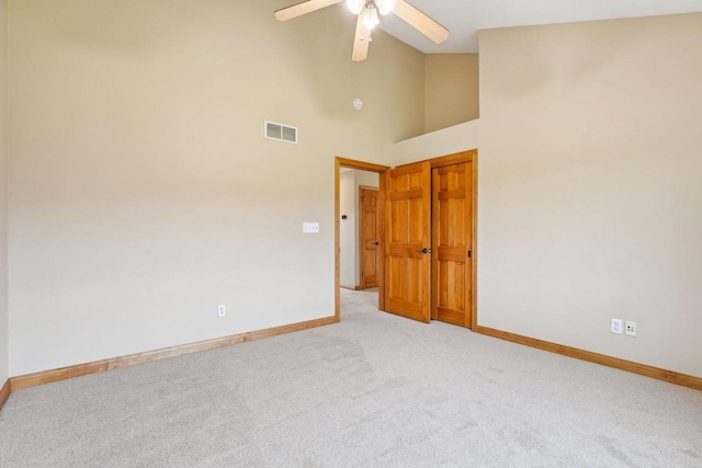 empty room featuring baseboards, light colored carpet, a ceiling fan, and high vaulted ceiling