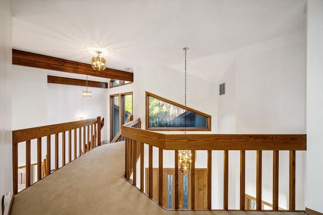corridor with a chandelier, an upstairs landing, carpet flooring, and beam ceiling