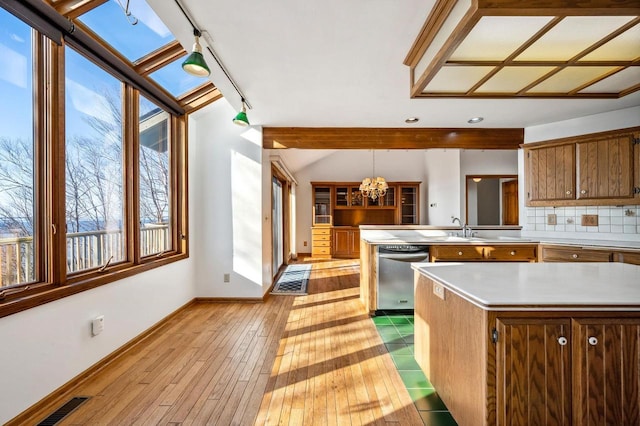 kitchen featuring dishwasher, baseboards, a chandelier, light countertops, and a peninsula