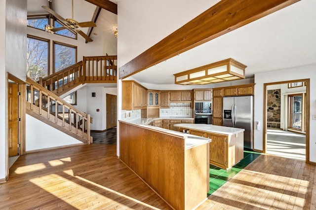 kitchen featuring stainless steel appliances, brown cabinets, hardwood / wood-style flooring, high vaulted ceiling, and a kitchen island