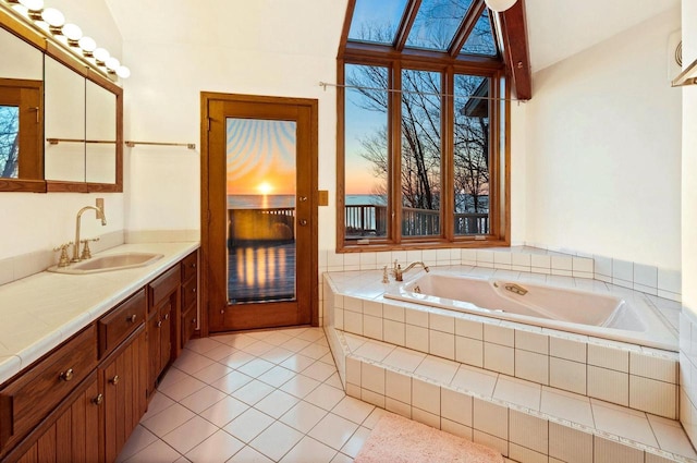full bath featuring a garden tub, tile patterned floors, lofted ceiling, and vanity