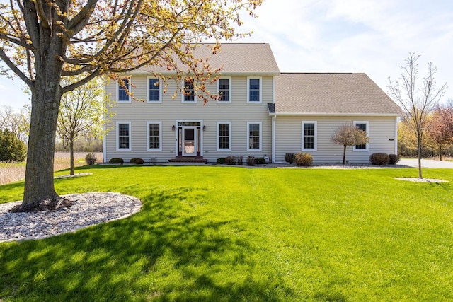 colonial house featuring a front yard and roof with shingles