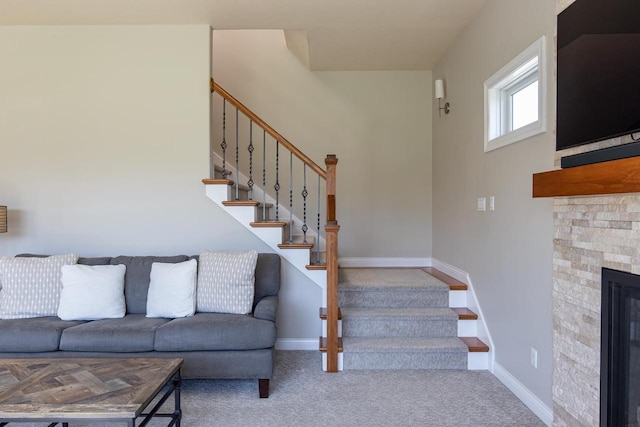 carpeted living area with stairway, baseboards, and a fireplace