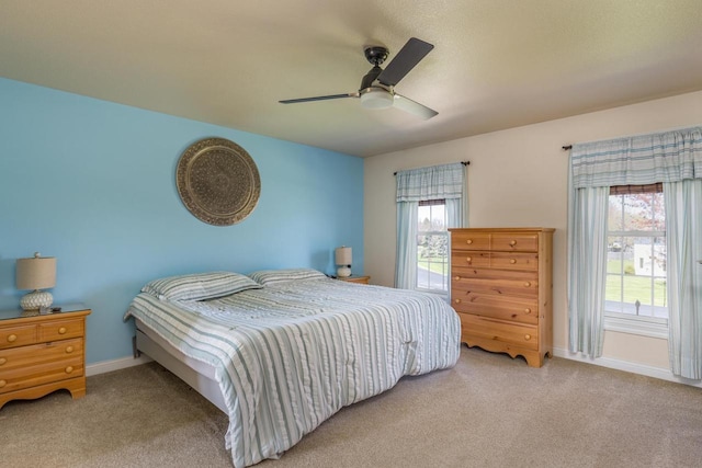 carpeted bedroom with multiple windows, baseboards, and ceiling fan