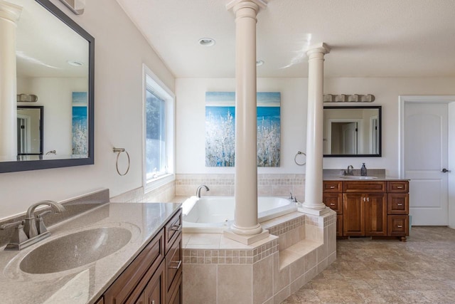 bathroom with ornate columns, a garden tub, and two vanities