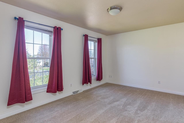 unfurnished room featuring healthy amount of natural light, carpet, and baseboards