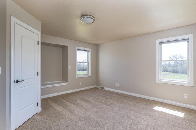 empty room featuring light carpet and baseboards