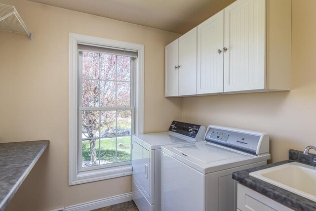 washroom with cabinet space, independent washer and dryer, and baseboards