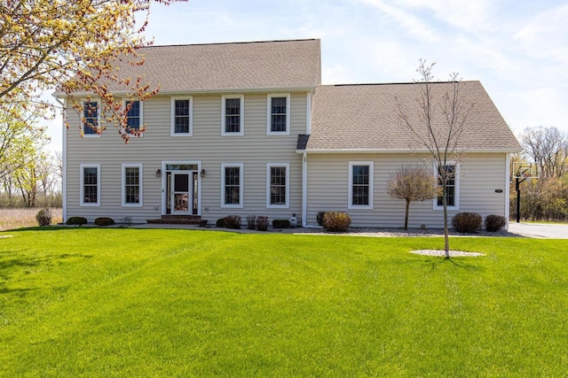 colonial house with a front lawn and a shingled roof