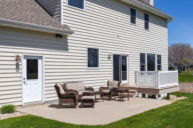 back of house with a shingled roof, a patio, an outdoor living space, a wooden deck, and a chimney