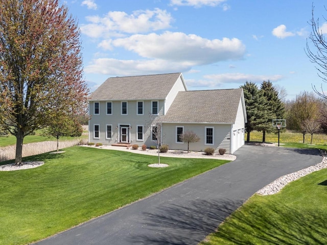 colonial-style house featuring a front lawn, a garage, driveway, and a shingled roof