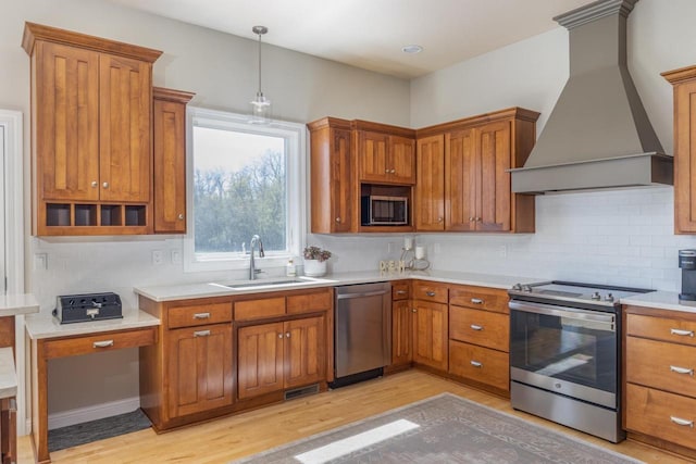 kitchen featuring appliances with stainless steel finishes, custom exhaust hood, a sink, light wood-type flooring, and brown cabinetry