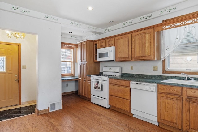 1214 S 17th St, Sheboygan, WI 53081 - kitchen with white appliances, a sink, brown cabinetry, a chandelier, and recessed lighting
