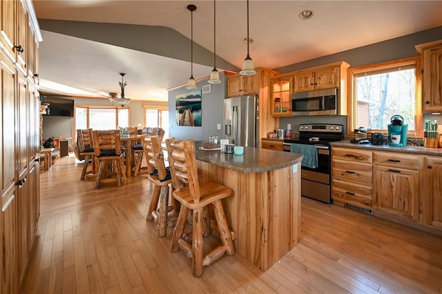 W5937 Ross Rd, Trego, WI 54888 - kitchen with appliances with stainless steel finishes, light wood-type flooring, a kitchen island, a breakfast bar, and decorative light fixtures