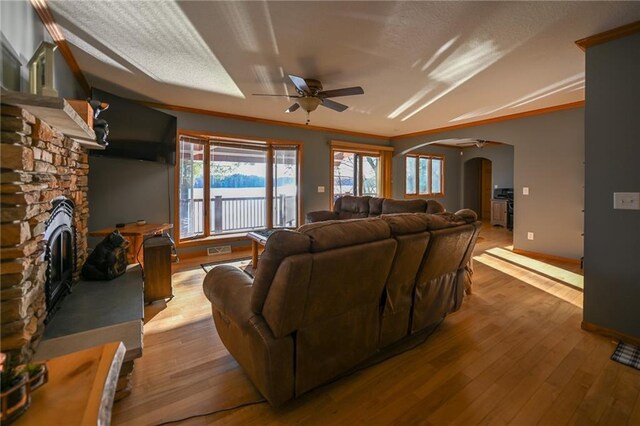 W5937 Ross Rd, Trego, WI 54888 - living area with arched walkways, ceiling fan, hardwood / wood-style floors, a stone fireplace, and baseboards