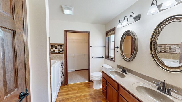 421 John Michael Dr, Jefferson, WI 53549 - bathroom featuring wood finished floors, toilet, a walk in closet, and double vanity