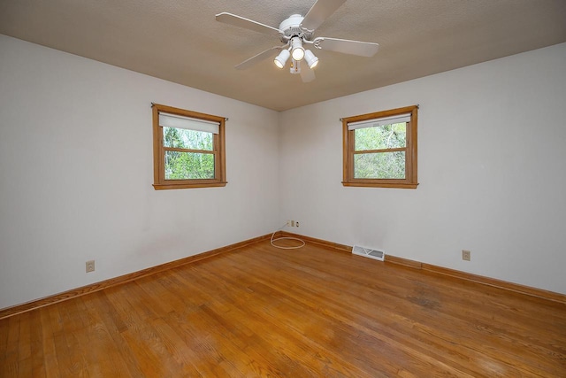 unfurnished room featuring wood finished floors, baseboards, and a ceiling fan