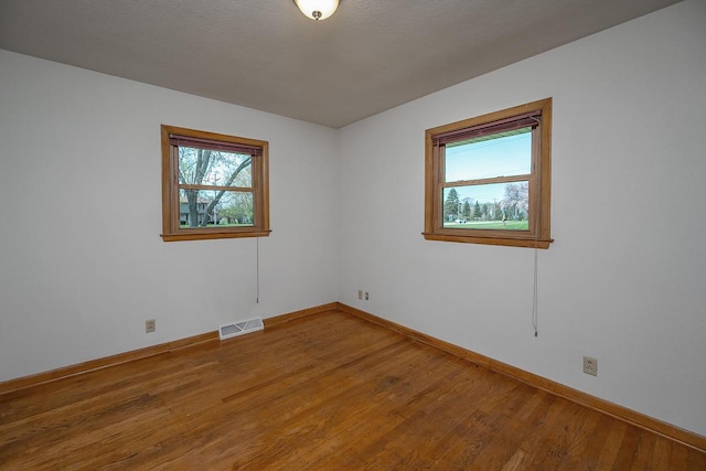 spare room with plenty of natural light, light wood-style floors, and baseboards