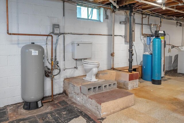 below grade area featuring tile patterned floors, a water softener, washer / dryer, and a water pressure tank
