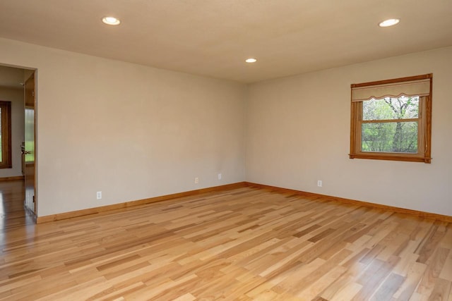 spare room featuring light wood finished floors, baseboards, and recessed lighting