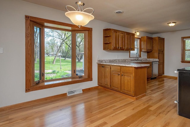 kitchen featuring a peninsula, light countertops, brown cabinetry, light wood-type flooring, and open shelves