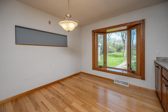 unfurnished dining area with baseboards and light wood-type flooring