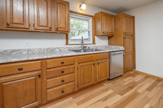 kitchen featuring dishwasher, a sink, light wood-style flooring, and light countertops