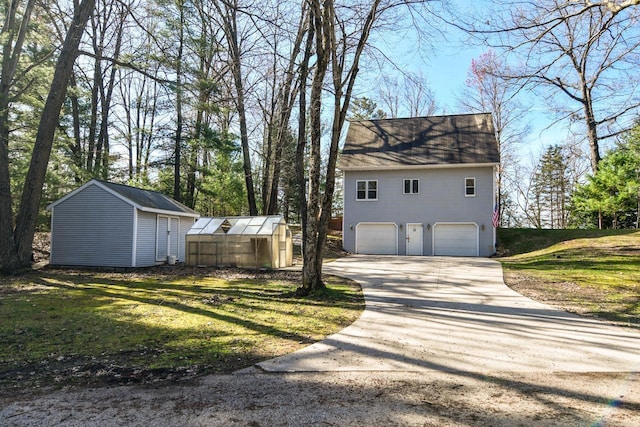6615 Birchwood Shores Ln, Oconto Falls, WI 54154 - view of property exterior featuring an attached garage, an outdoor structure, concrete driveway, a greenhouse, and a yard