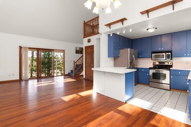 6615 Birchwood Shores Ln, Oconto Falls, WI 54154 - kitchen with appliances with stainless steel finishes, blue cabinets, track lighting, a chandelier, and light wood-style flooring