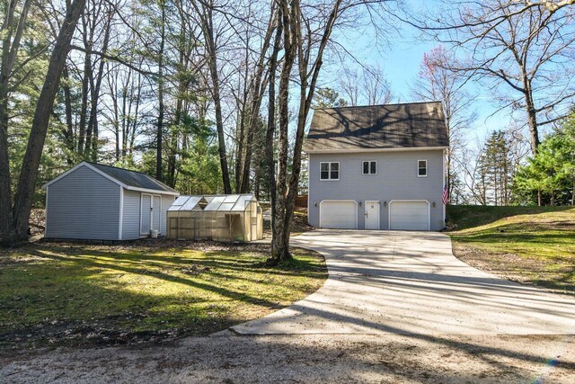 6615 Birchwood Shores Ln, Oconto Falls, WI 54154 - view of property exterior featuring an attached garage, an outdoor structure, concrete driveway, a greenhouse, and a yard