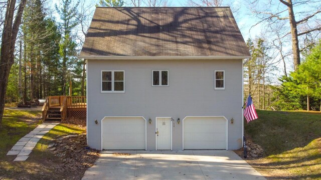 6615 Birchwood Shores Ln, Oconto Falls, WI 54154 - view of side of home with an attached garage, a shingled roof, concrete driveway, and a wooden deck