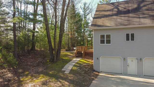 6615 Birchwood Shores Ln, Oconto Falls, WI 54154 - view of home's exterior featuring a shingled roof, a deck, an attached garage, and concrete driveway
