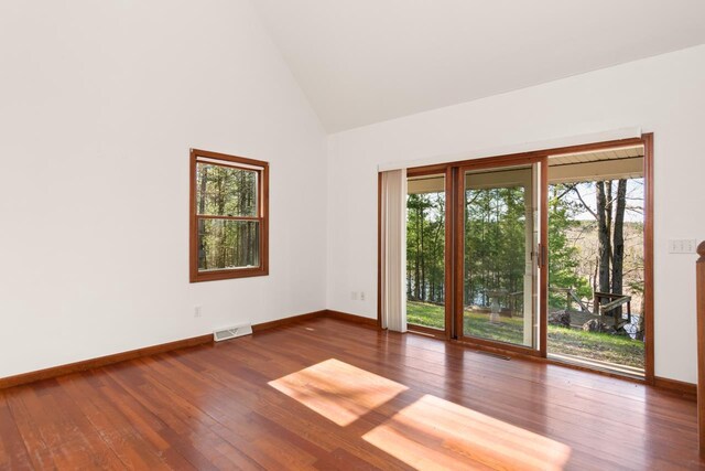 6615 Birchwood Shores Ln, Oconto Falls, WI 54154 - spare room featuring plenty of natural light, baseboards, high vaulted ceiling, and wood-type flooring