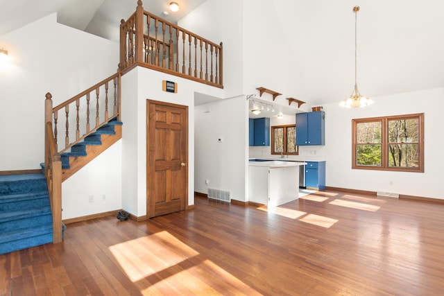6615 Birchwood Shores Ln, Oconto Falls, WI 54154 - unfurnished living room with stairs, wood finished floors, a chandelier, baseboards, and high vaulted ceiling