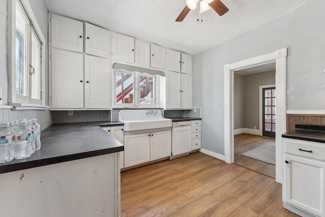 332 La Valle St, Reedsburg, WI 53959 - kitchen featuring a sink, dark countertops, light wood-style flooring, and white cabinets