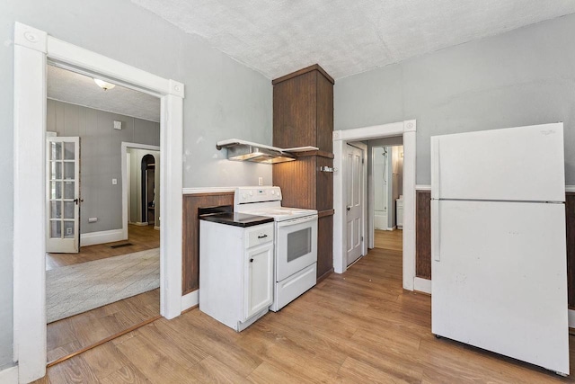 332 La Valle St, Reedsburg, WI 53959 - kitchen featuring white appliances, light wood-type flooring, a textured ceiling, white cabinets, and arched walkways