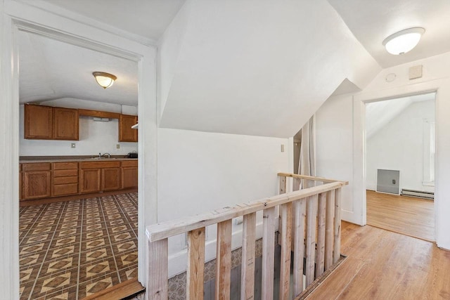 332 La Valle St, Reedsburg, WI 53959 - hallway with a baseboard heating unit, vaulted ceiling, an upstairs landing, a sink, and light wood-style flooring