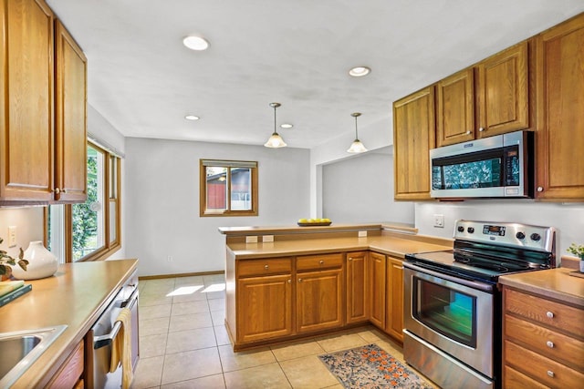 407 Edward St, Verona, WI 53593 - kitchen featuring appliances with stainless steel finishes, a peninsula, brown cabinetry, light tile patterned floors, and light countertops