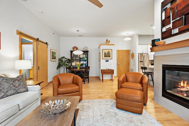 530 W Doty St Unit 105, Madison, WI 53703 - living area with a barn door, light wood finished floors, a glass covered fireplace, and ceiling fan