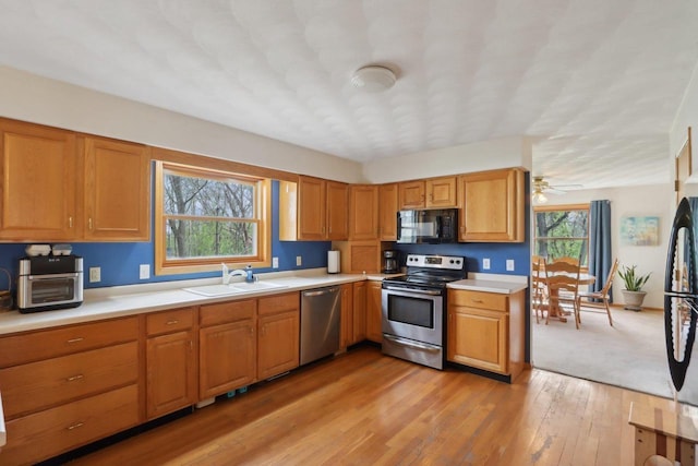 7938 E Hwy 59, Milton, WI 53563 - kitchen with black appliances, a sink, light countertops, light wood finished floors, and brown cabinetry