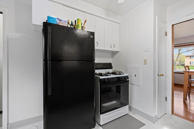 9517 W Capitol Dr, Milwaukee, WI 53222 - kitchen with freestanding refrigerator, gas range, light marble finish flooring, white cabinets, and baseboards