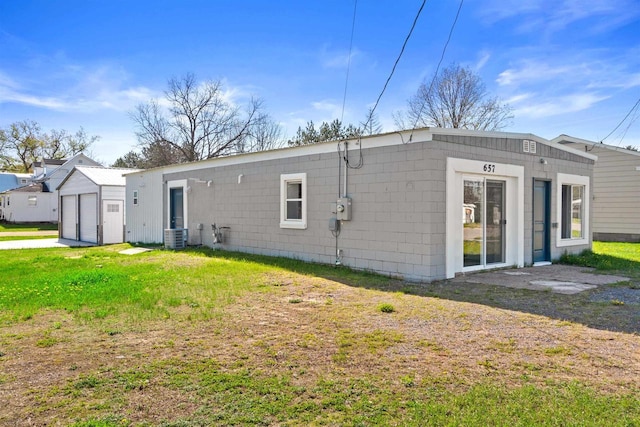 657 Elm St, Black River Falls, WI 54615 - back of property featuring a detached garage, a lawn, cooling unit, and concrete block siding