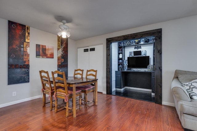 dining room with wood finished floors, a ceiling fan, and baseboards