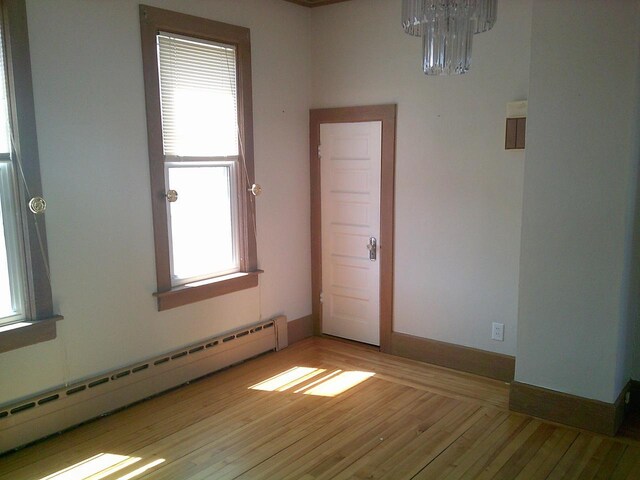 2309 Jefferson St, Two Rivers, WI 54241 - empty room featuring a baseboard radiator, a chandelier, and light wood finished floors