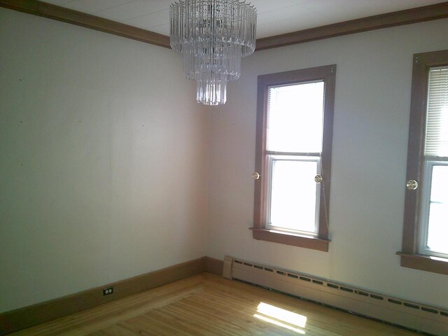 2309 Jefferson St, Two Rivers, WI 54241 - unfurnished room featuring a baseboard radiator, a chandelier, light wood-type flooring, and baseboards