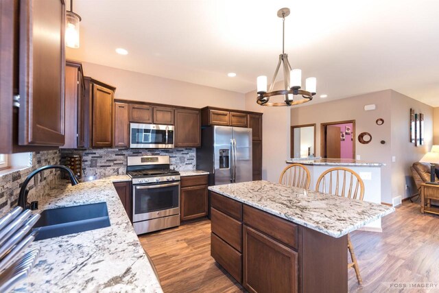 222 Blooming Leaf Way, Verona, WI 53593 - kitchen with stainless steel appliances, a sink, a chandelier, a kitchen island, and tasteful backsplash
