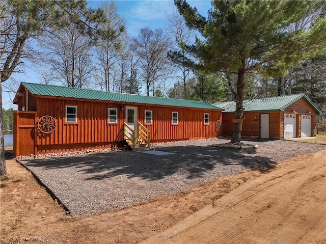 W7339 Pair O Lakes Rd, Spooner, WI 54801 - rustic home with entry steps, board and batten siding, metal roof, a garage, and driveway