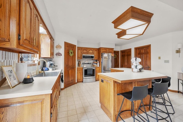 2108 Lawrence Dr, De Pere, WI 54115 - kitchen with appliances with stainless steel finishes, a sink, light countertops, a breakfast bar area, and a kitchen island